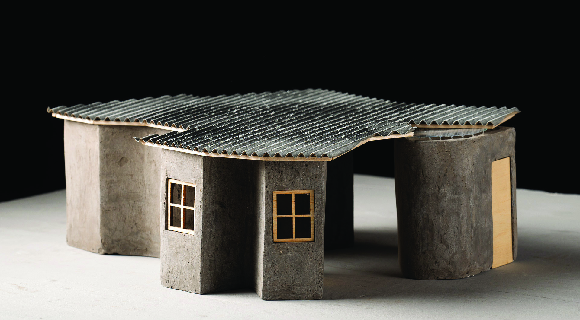 Physical architectural model of the worker's house showing the corrugated roof, curved concrete modules, and the overall organic plan