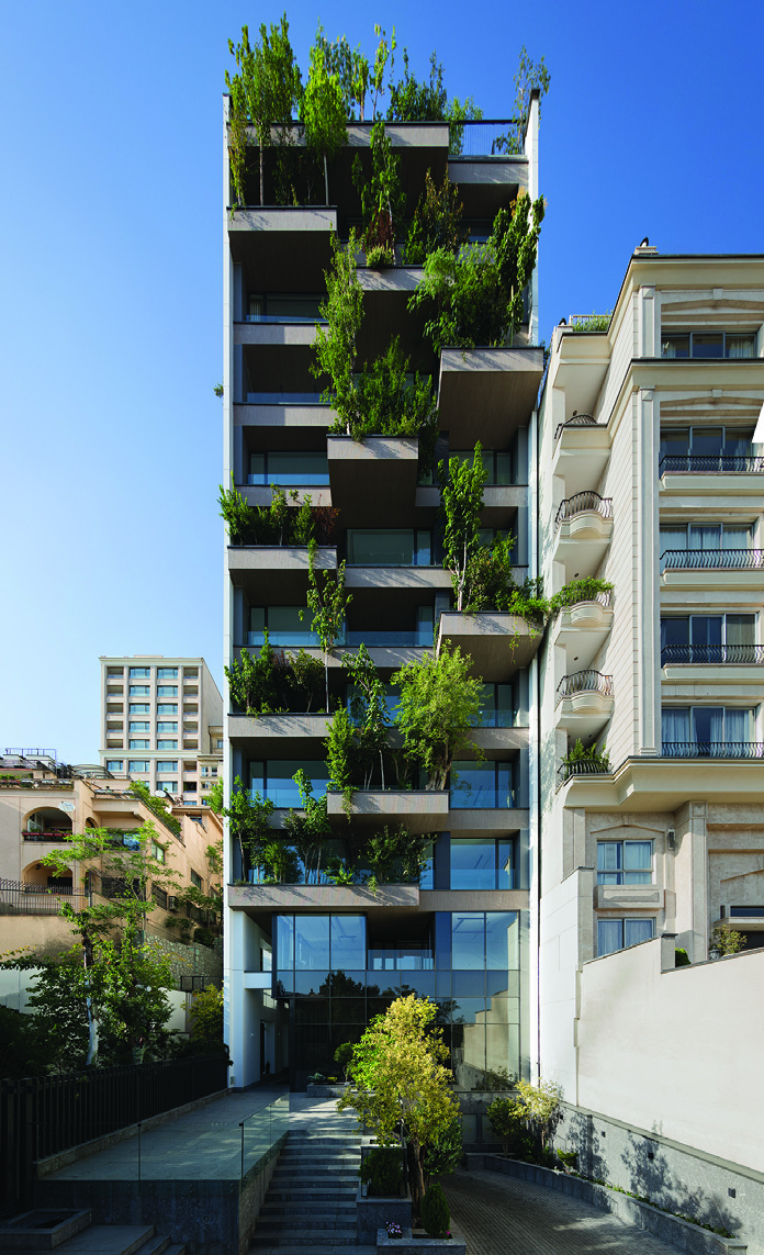 Full-height view of the Persica building's south facade showing the staggered concrete planters with mature trees and shrubs growing on every level