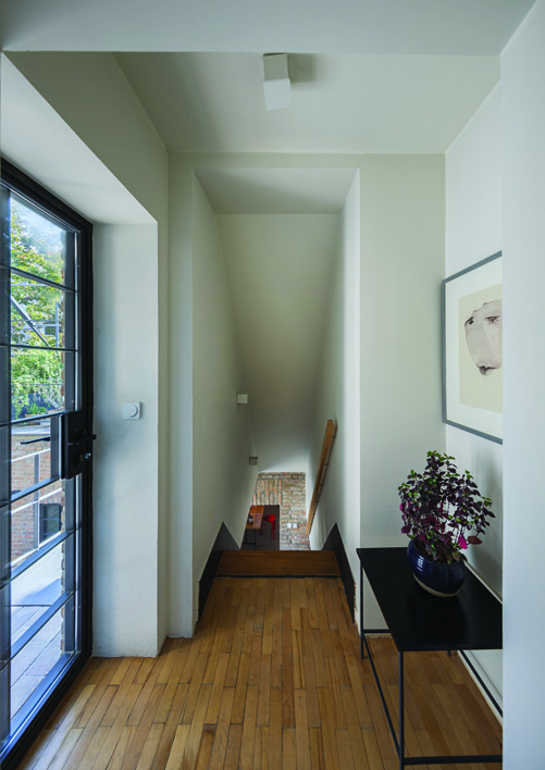 Upper landing of the stairwell showing steel railing, brick walls, and natural light from above