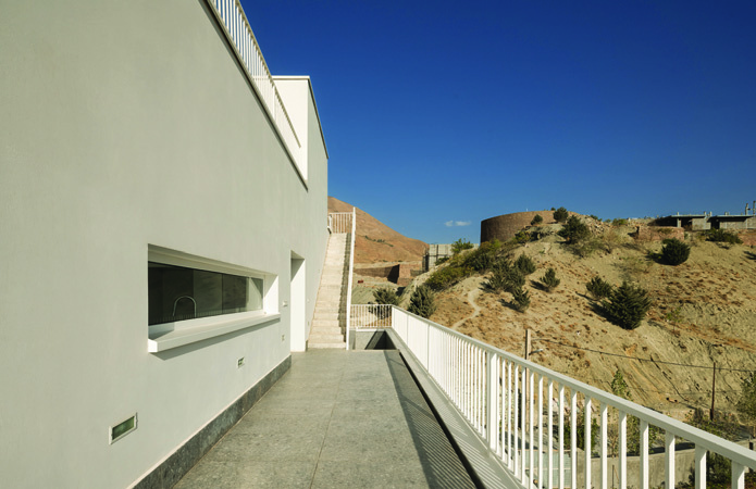 Covered walkway and ramp along the building's hillside with the parking level below