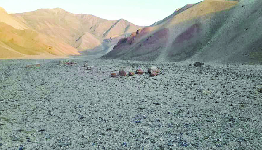 Barren desert landscape of Badakhshan with scattered boulders and colourful mountain slopes