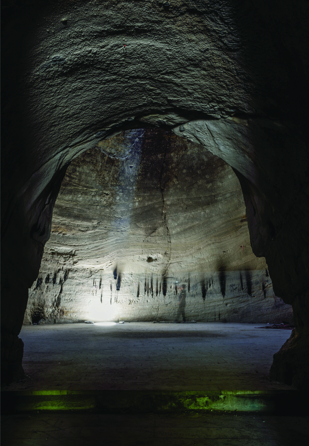 Ancient stone gravestones scattered on a hillside in the old Badamyar cemetery, with barren mountains rising behind