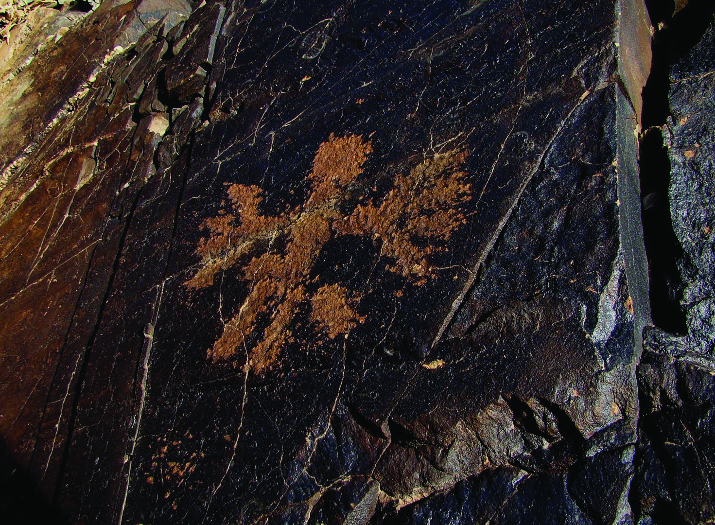 Petroglyph at Darreh Negaran showing a human figure with arms spread in a star pattern on dark rock