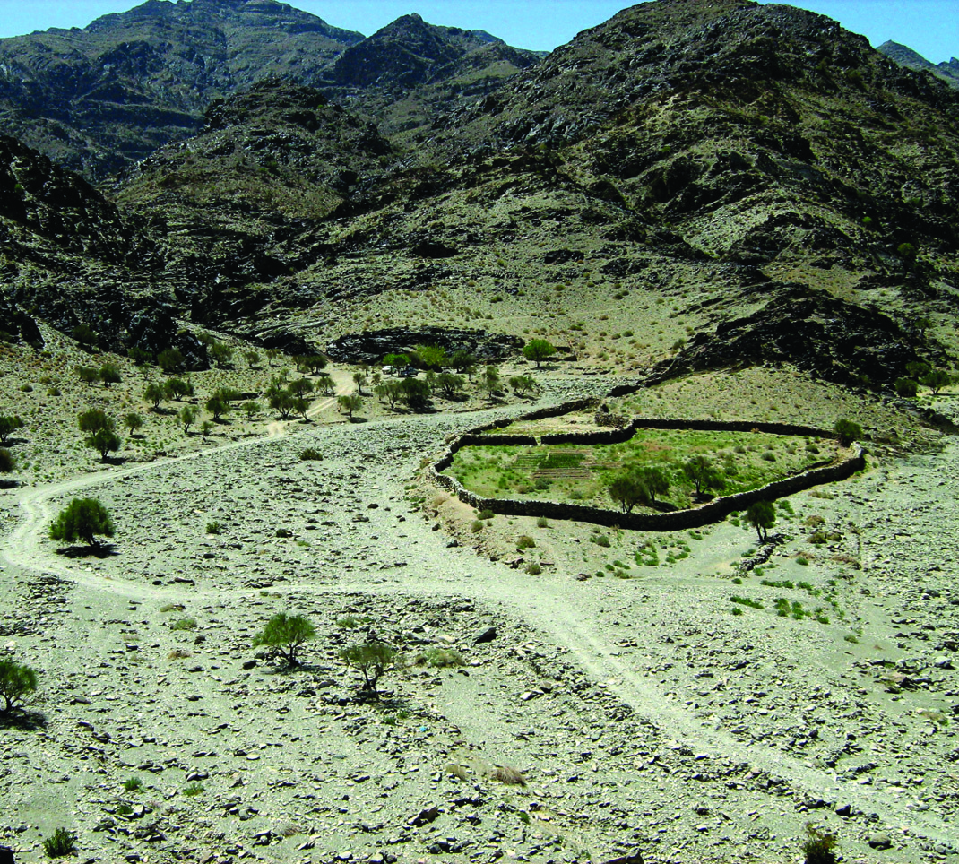 Mountainous valley of Darreh Negaran in Baluchestan with a green oasis surrounded by rugged peaks