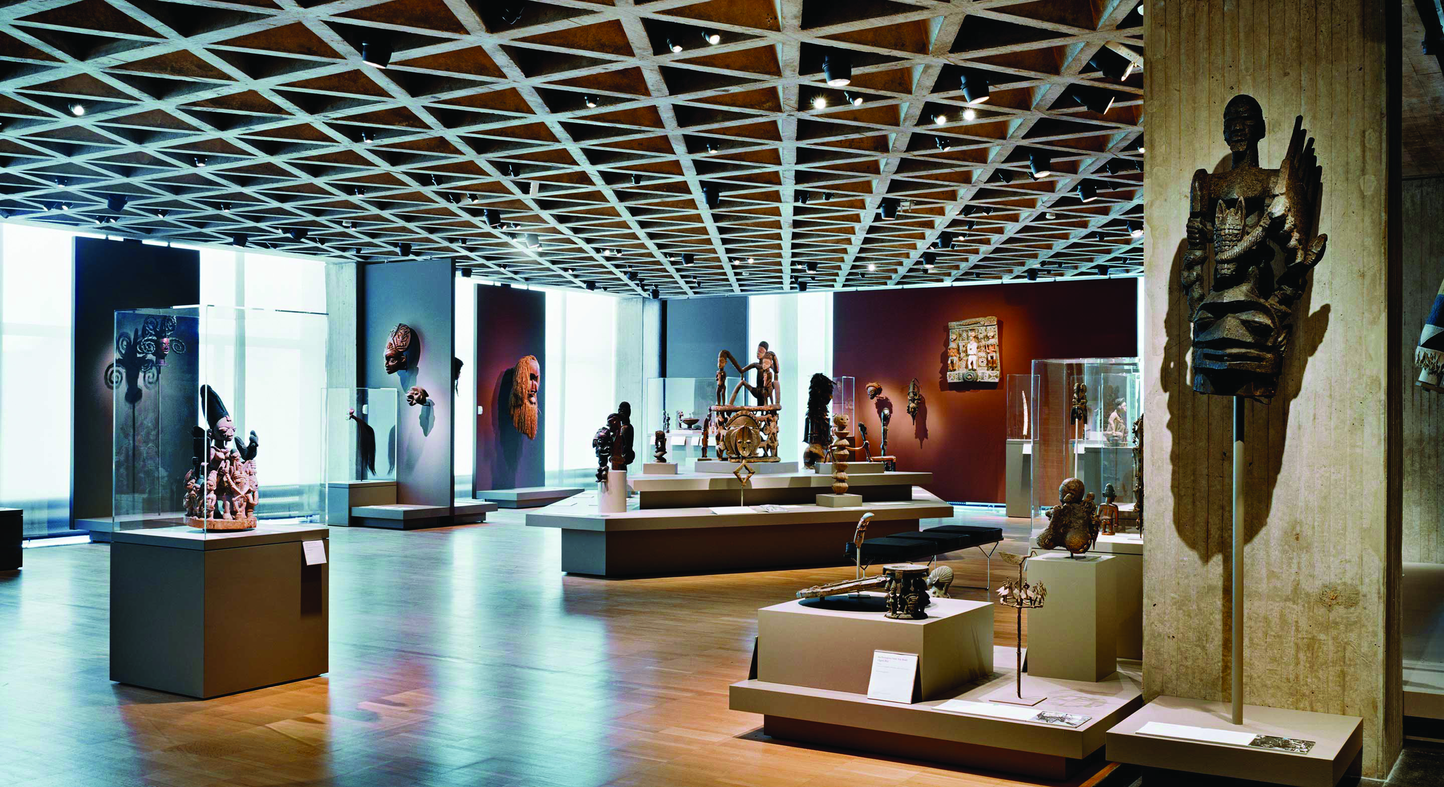 Color photograph of the Yale Art Gallery displaying African art beneath the tetrahedral concrete ceiling structure designed by Louis Kahn