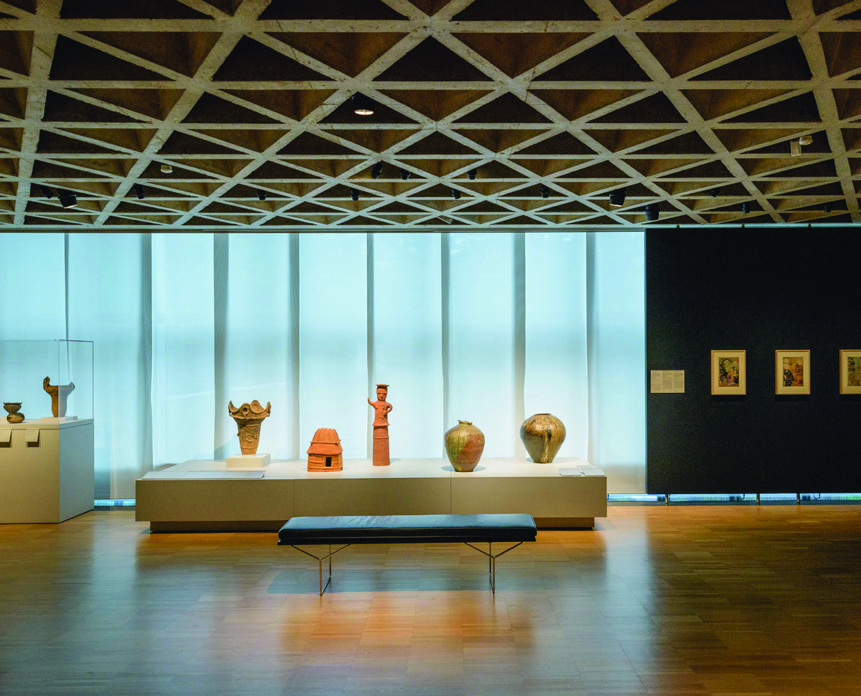 Color photograph of a ceramics display at the Yale Art Gallery, with natural window light illuminating the pottery and vessels on glass shelves
