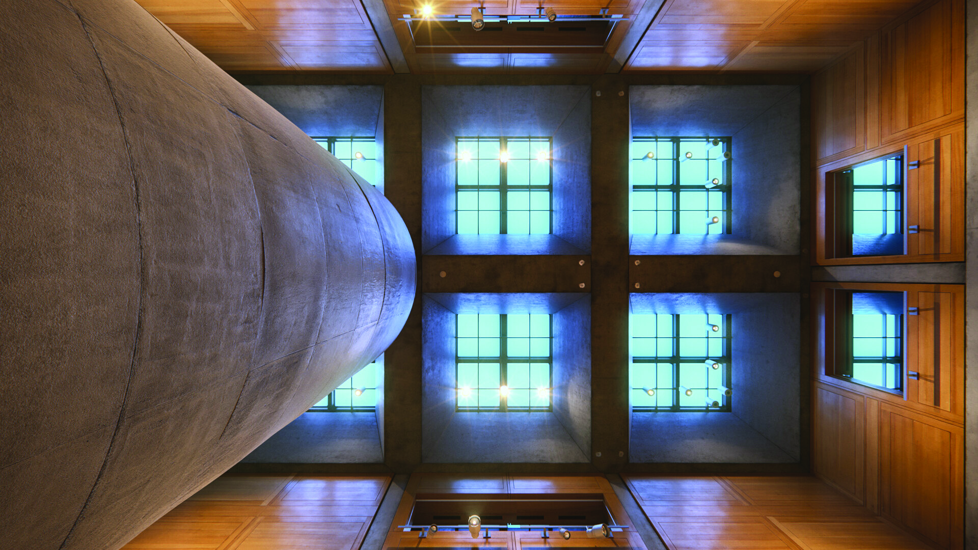 Looking upward at the library court skylight, showing the V-shaped concrete beams and the blue light filtering through the glass ceiling structure