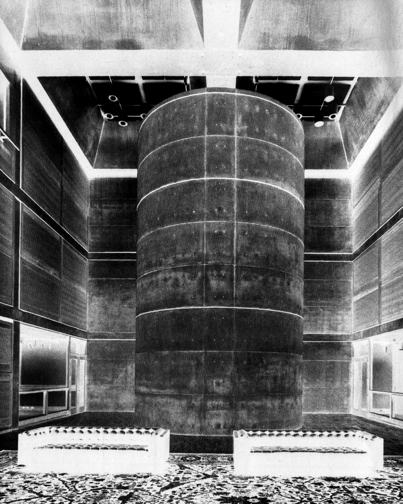 Black-and-white photograph of the library court showing the monumental concrete stair drum rising through the center, flanked by oak-paneled galleries on multiple levels with the skylight diffusers above
