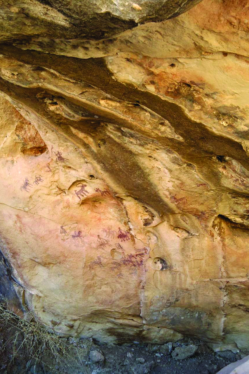A large rock shelter in Lorestan with ochre and red painted figures of animals and humans on a sandstone wall