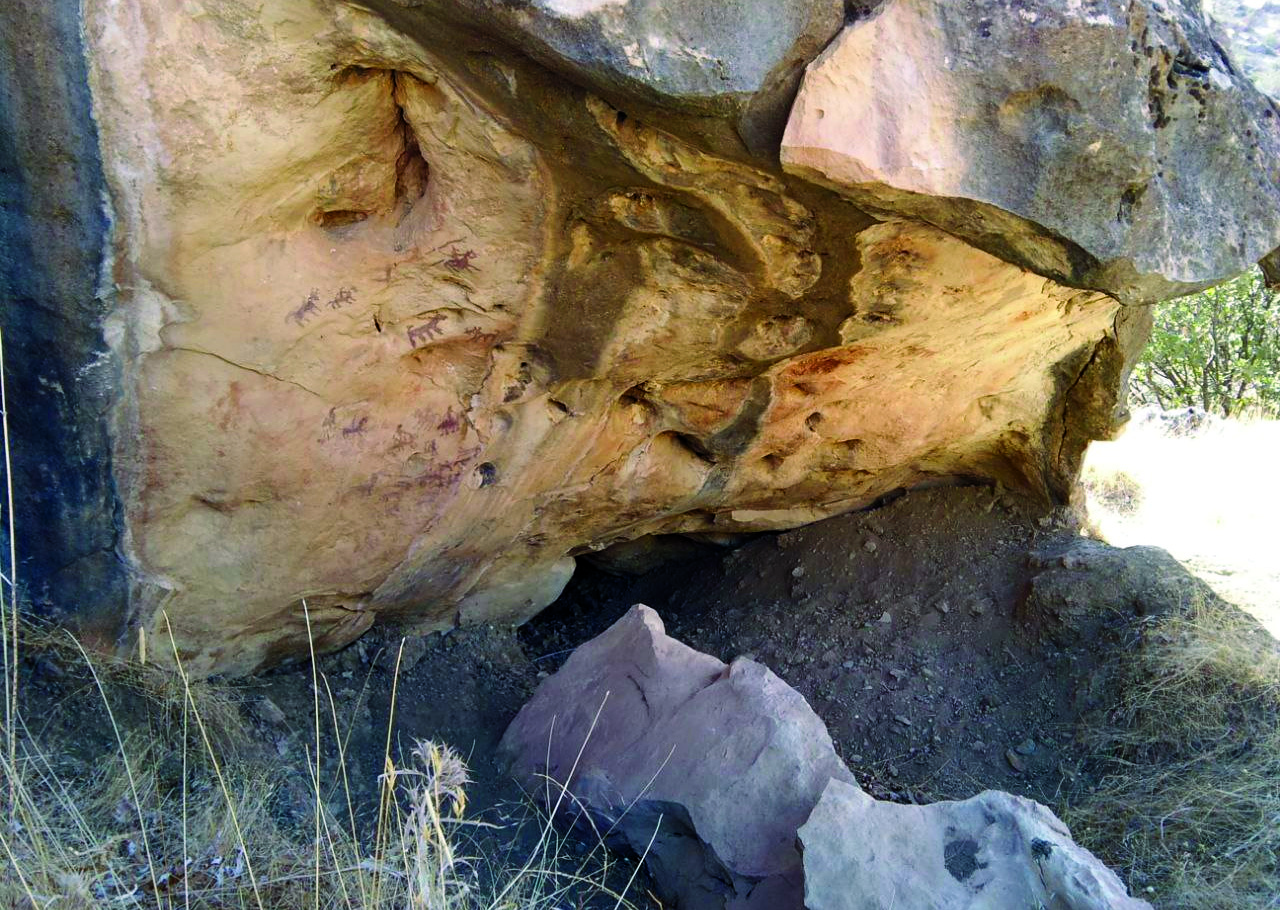 Exterior view of a rock shelter in Lorestan with painted figures visible on the underside of the overhanging sandstone boulder