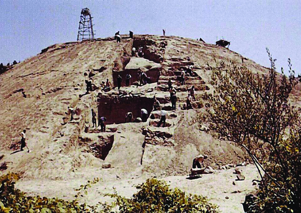 The archaeological mound of Marlik during excavation, showing workers on the stepped hillside