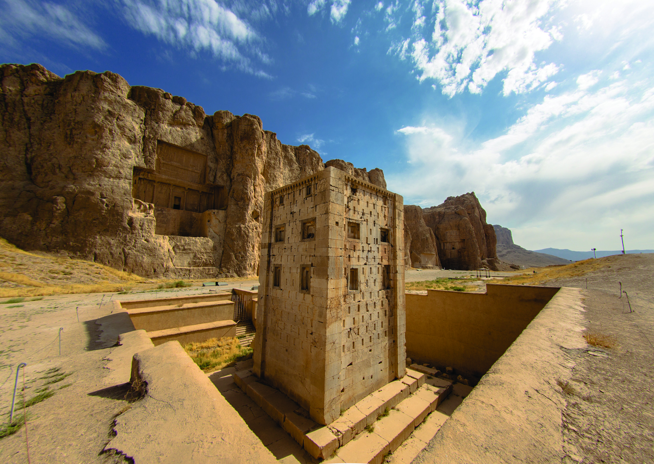 Naqsh-e Rostam site showing the Ka'ba-ye Zartosht cube-shaped stone structure in the foreground, with Achaemenid rock-cut royal tombs carved into the cliff face behind it