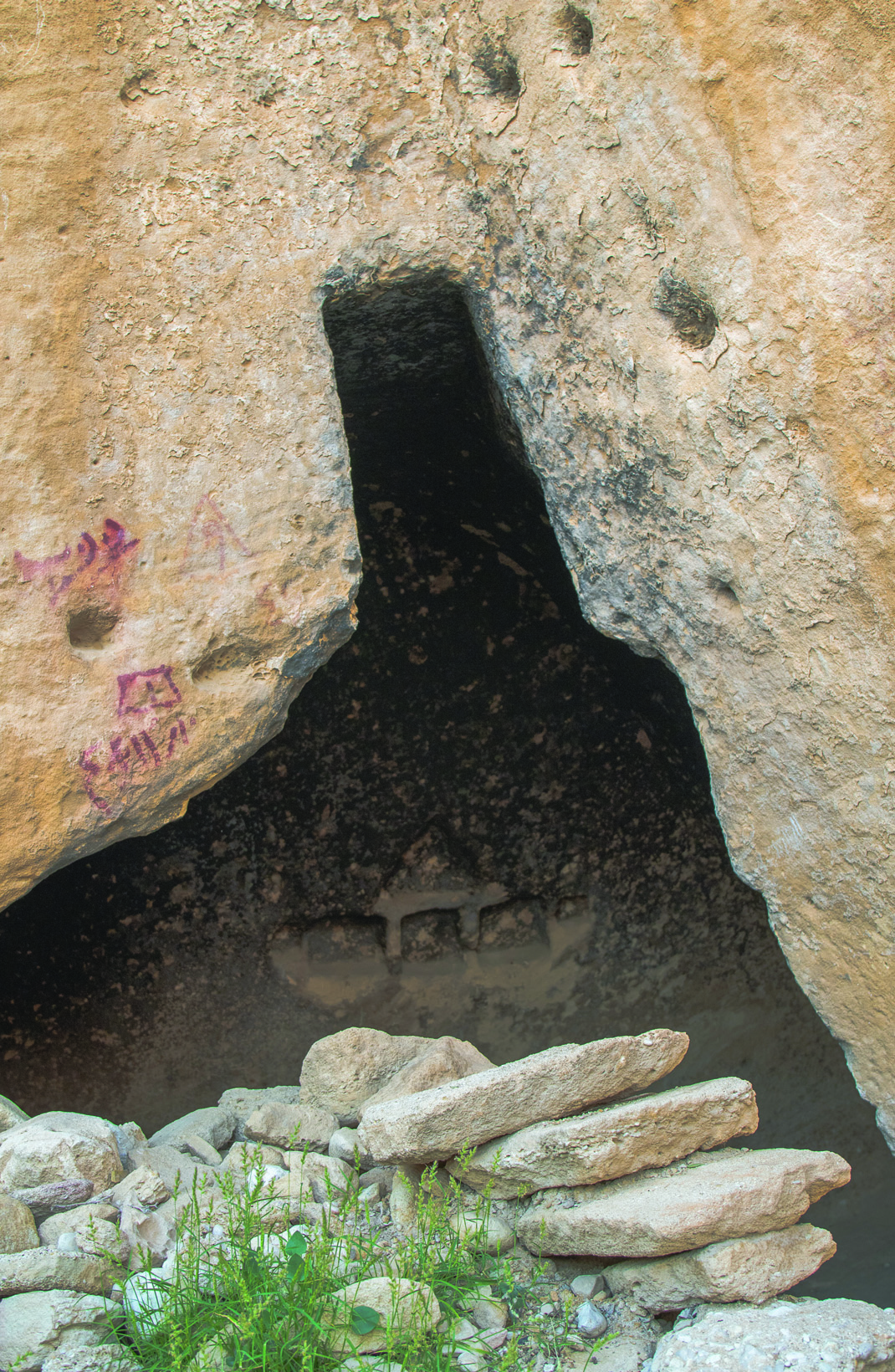 The entrance to a cave in Siraf with ancient rock carvings visible on the sandstone walls