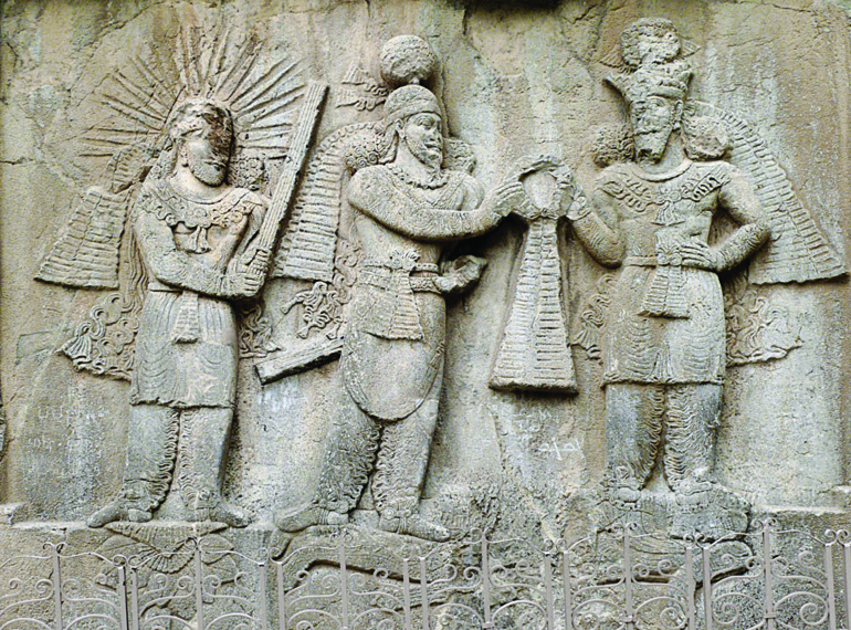Sasanian rock relief at Taq-e Bostan showing Ardeshir II standing between Mithra with radiant halo on the right and Ahura Mazda offering a ring on the left