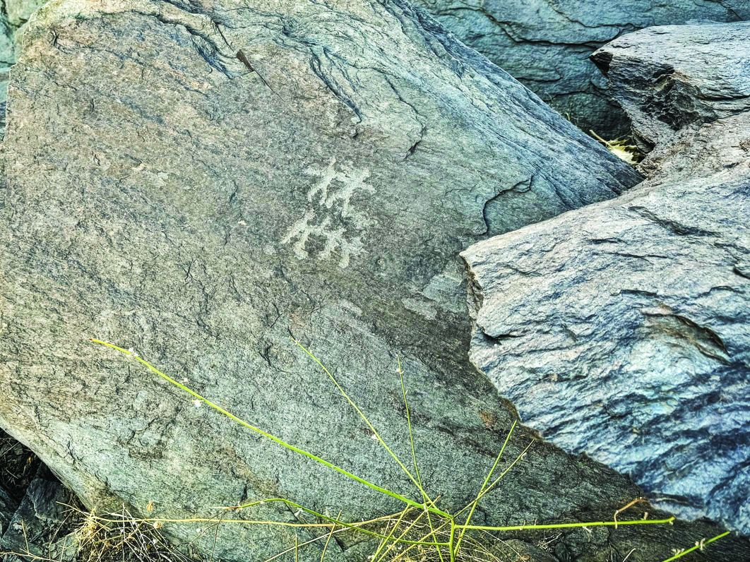 Teimareh petroglyph showing two small human figures in a dancing or ritual pose on grey rock