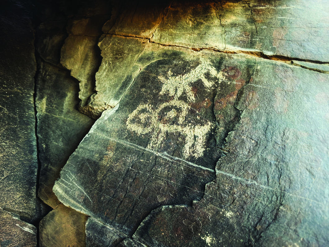 Teimareh petroglyph showing smaller figures nestled between the oversized horns of an ibex, symbolising protection