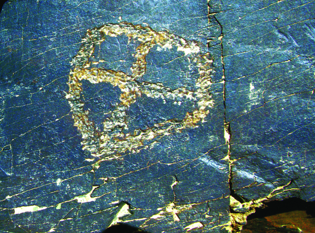 A deeply carved Mithraic cross (chelipa) symbol on blue-toned rock at Teimareh