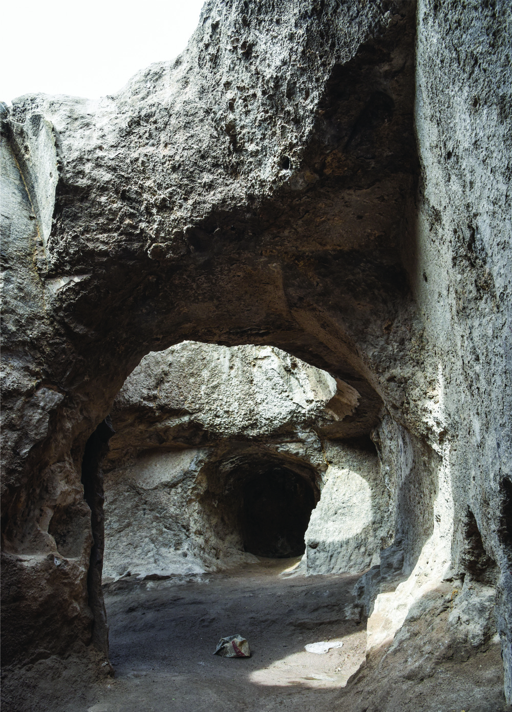 Rock-cut arched passages inside the Varjovi Mithraeum showing the layered natural stone surfaces and dark recesses