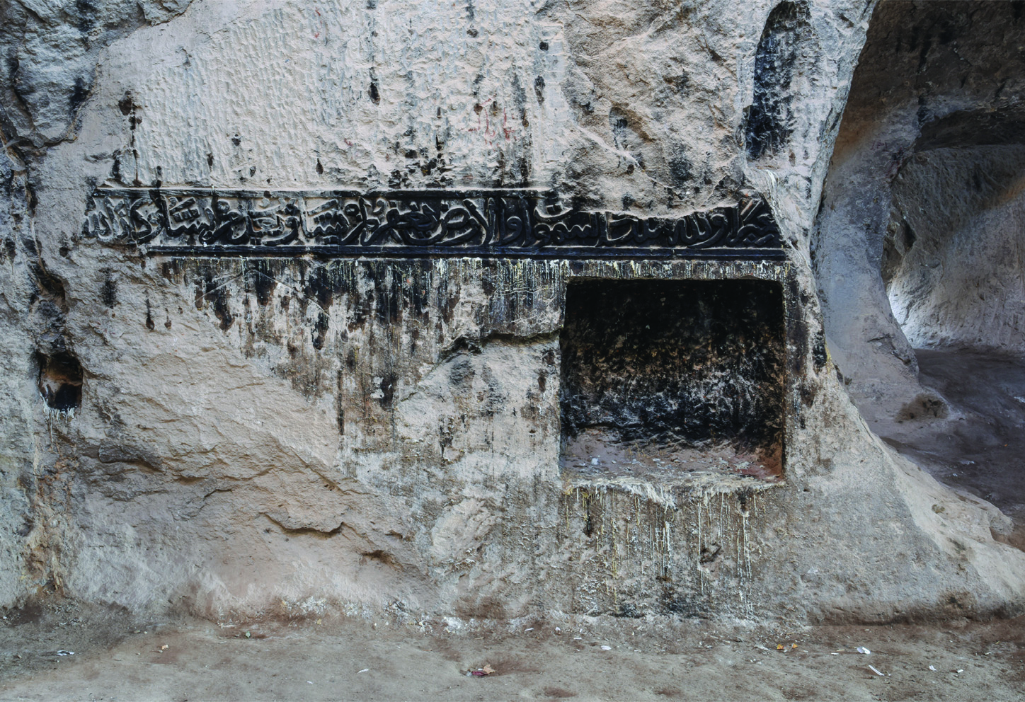 Islamic prayer niche (mihrab) carved into the rock wall of the Varjovi temple, with Arabic inscription in Naskh script above