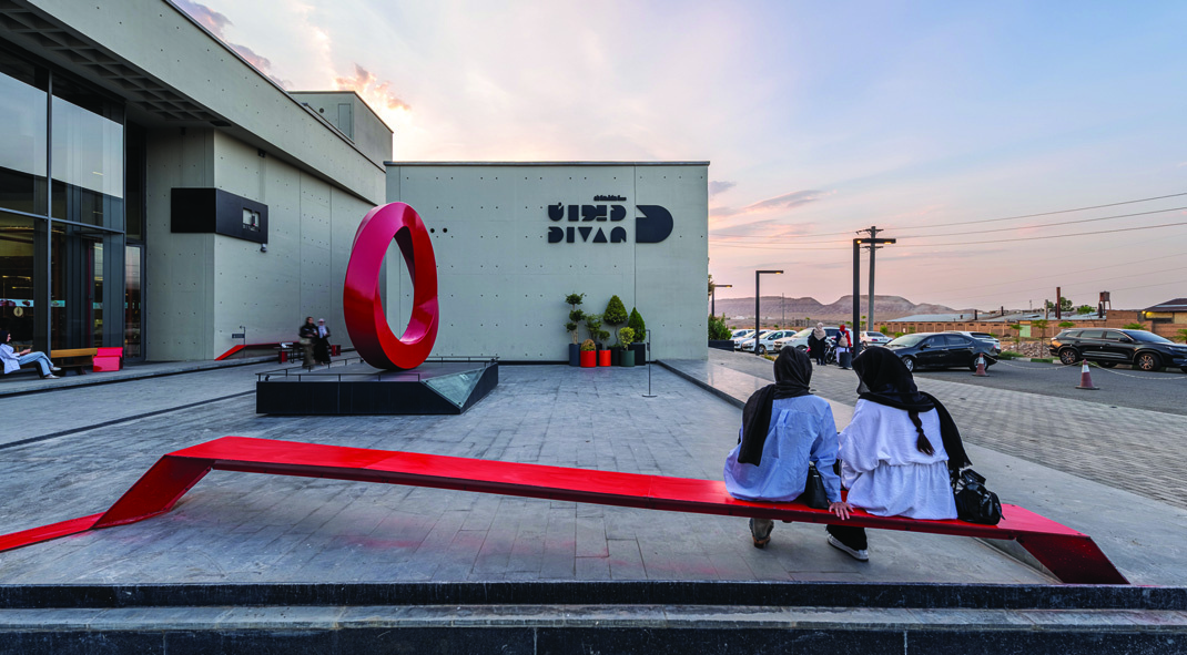 Divan Building, visitors on red bench in public plaza