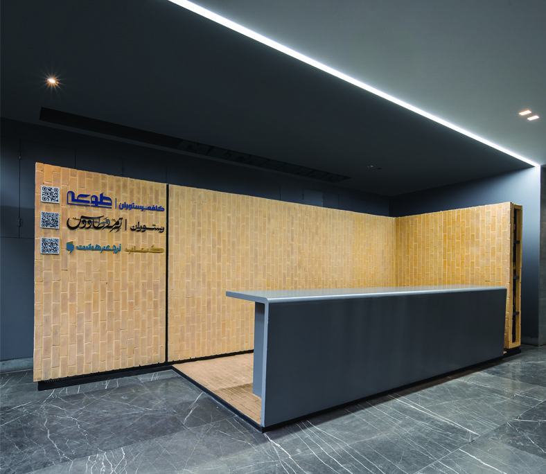 Interior reception area with a brick-clad wall bearing cafe and restaurant signage, a grey reception counter, dark polished floor, and linear ceiling lighting