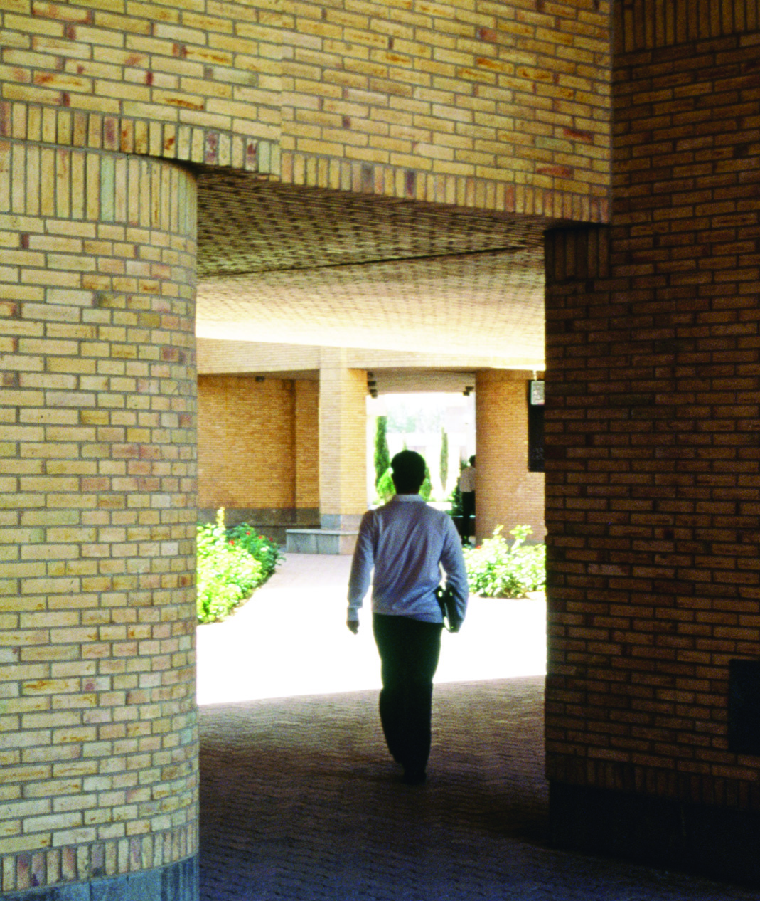 Student walking through a brick corridor passage between buildings
