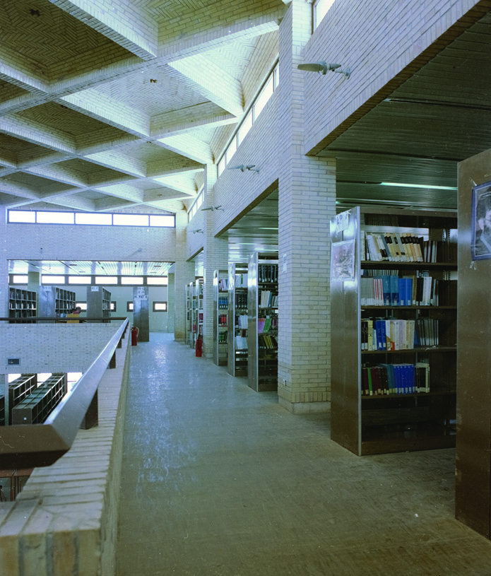 Central library interior with exposed brick ceiling structure, skylights, and book stacks