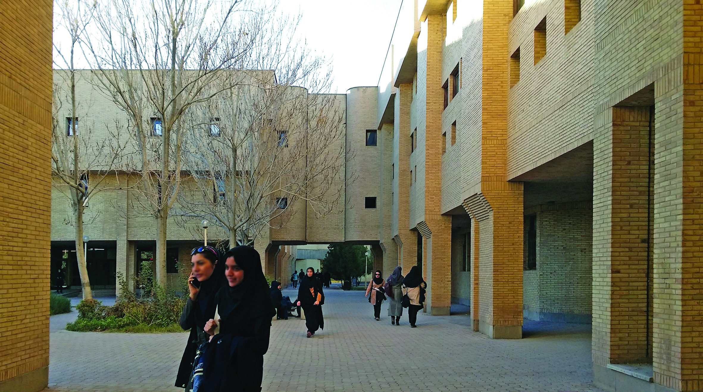 Students walking through a courtyard pathway between university buildings