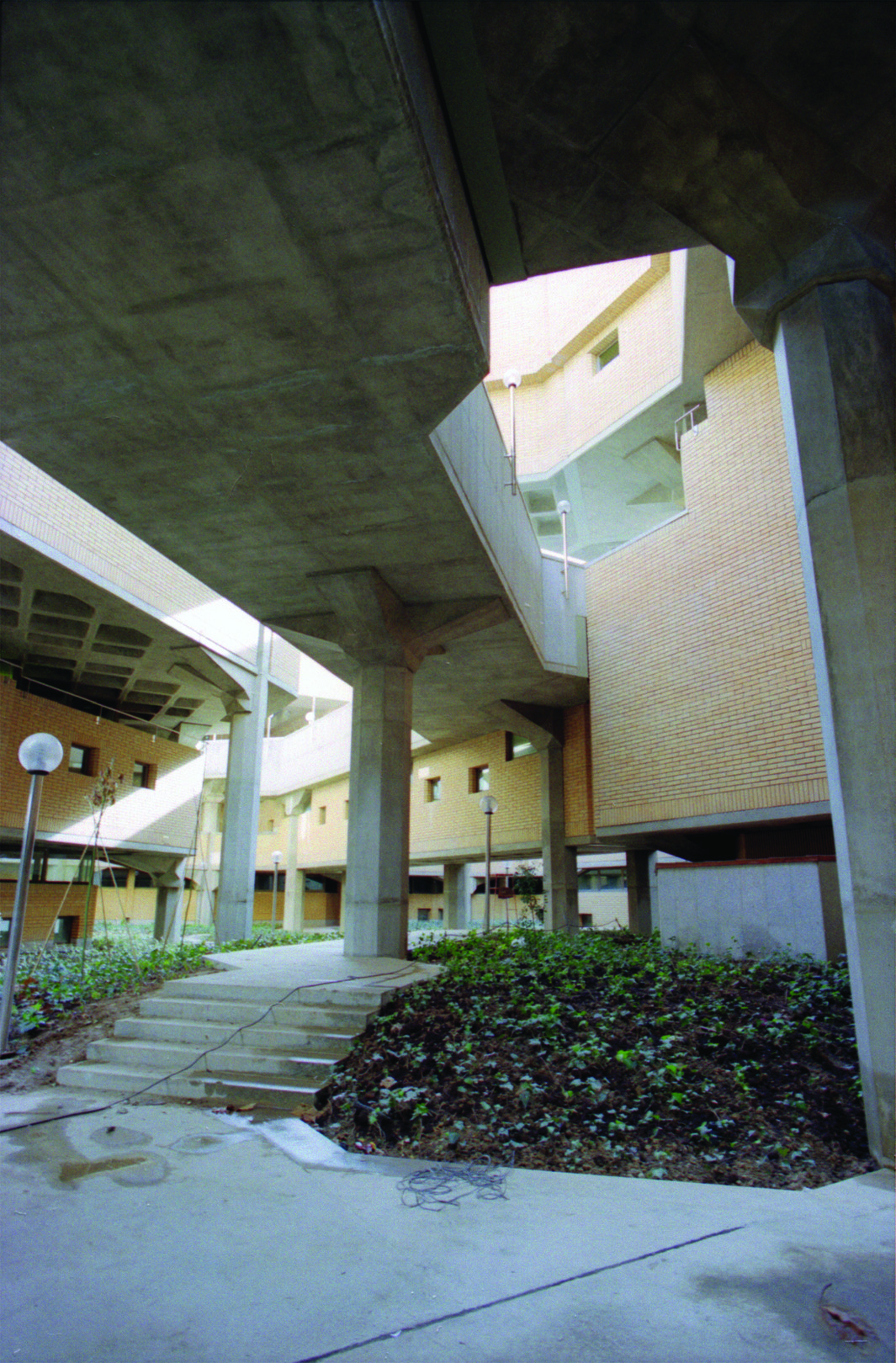 Exterior covered walkway with concrete columns and landscaped terraces