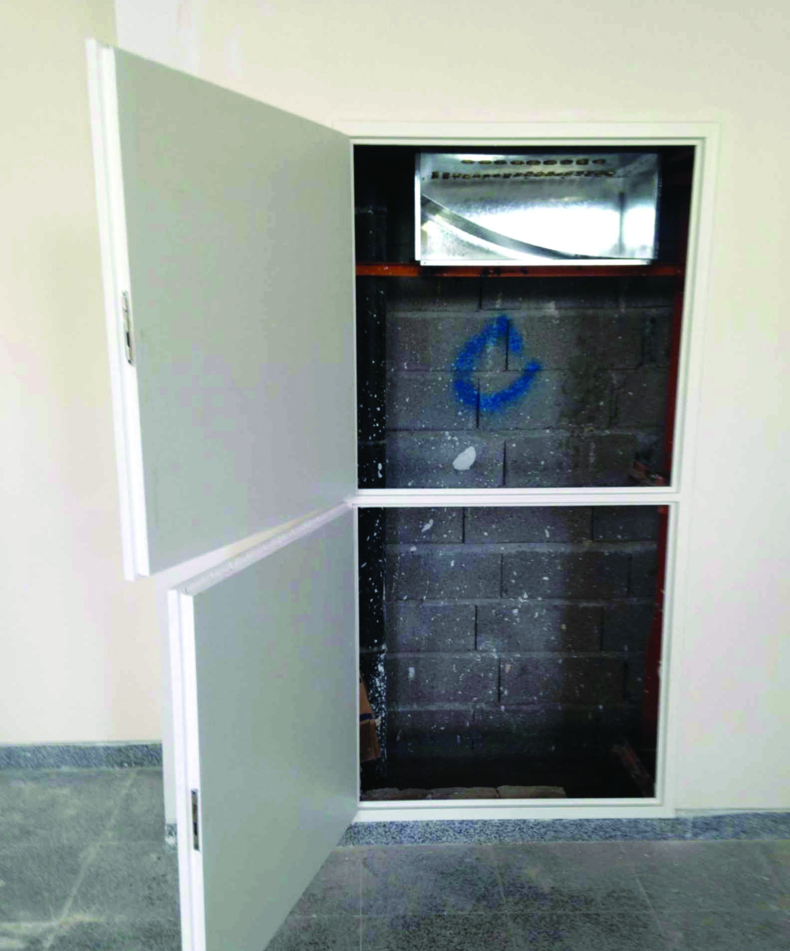 Utility access panel opened to reveal mechanical conduit shaft