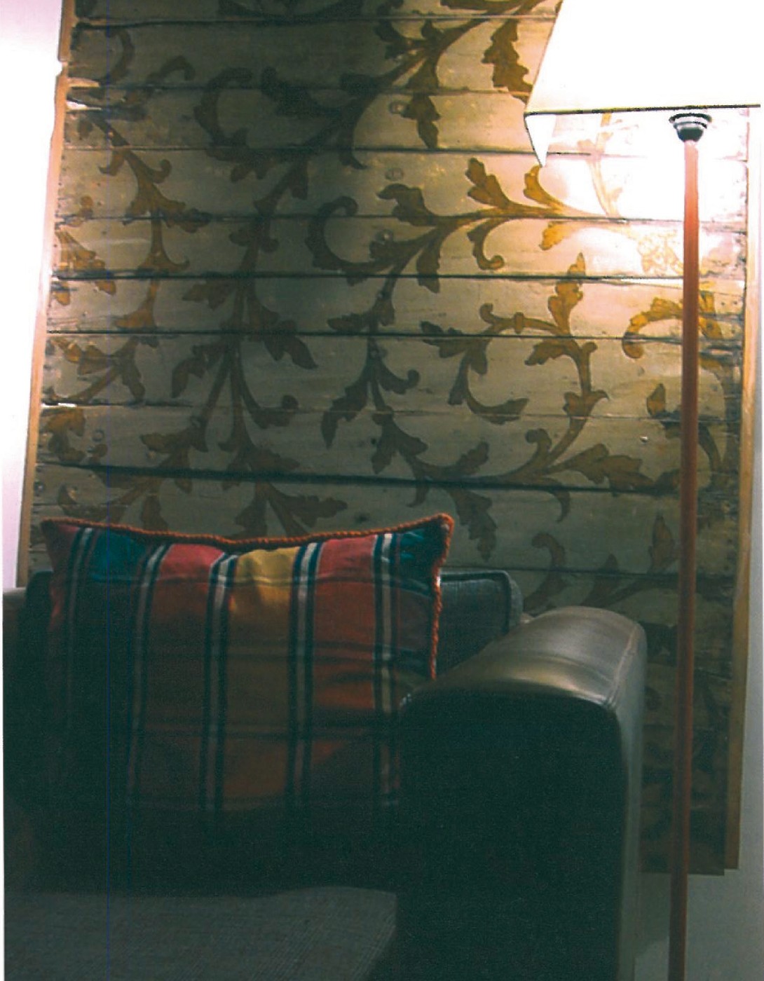 Wider view of the same room: tall floor lamp with circular shade, leather Club chair with plaid cushion, against a richly patterned arabesque wallpaper