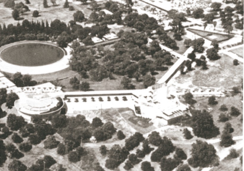 Aerial photograph of Frank Lloyd Wright's Florida Southern College — the round library building, low Administration block, and Ann Pfeiffer Chapel visible in the foreground among orange groves.