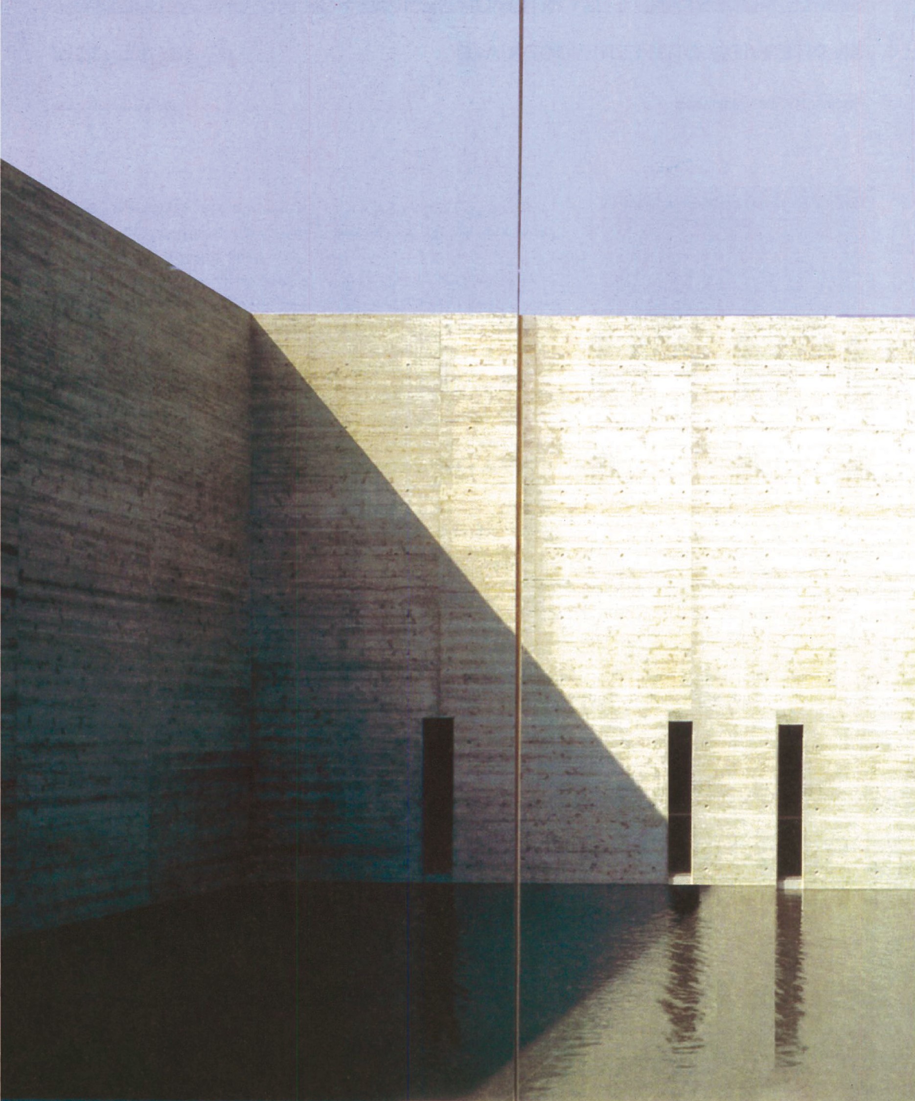Interior courtyard at Kaze-No-Oka: tall planes of dark concrete and stone surrounding a still water surface that reflects the sky
