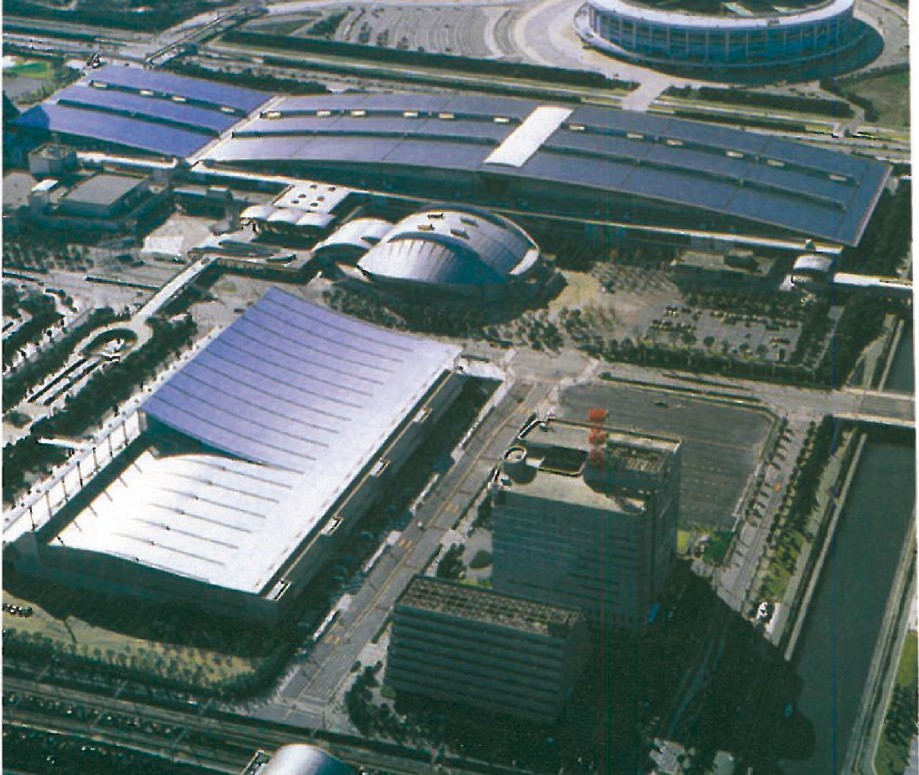 Aerial view of the Makuhari Messe convention complex in Chiba, Japan, showing the white tent-like roofs against the surrounding city