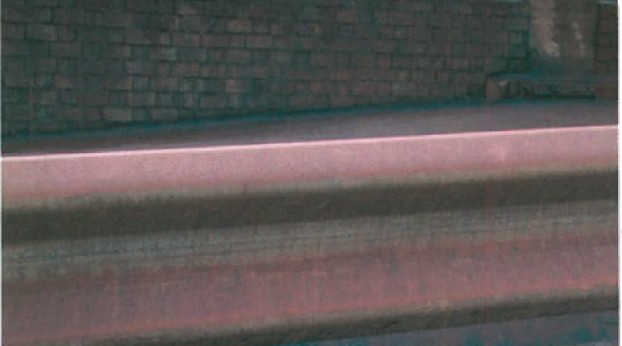 Close-up of a brick wall and rust-stained pipe showing the heavy particulate pollution at the site