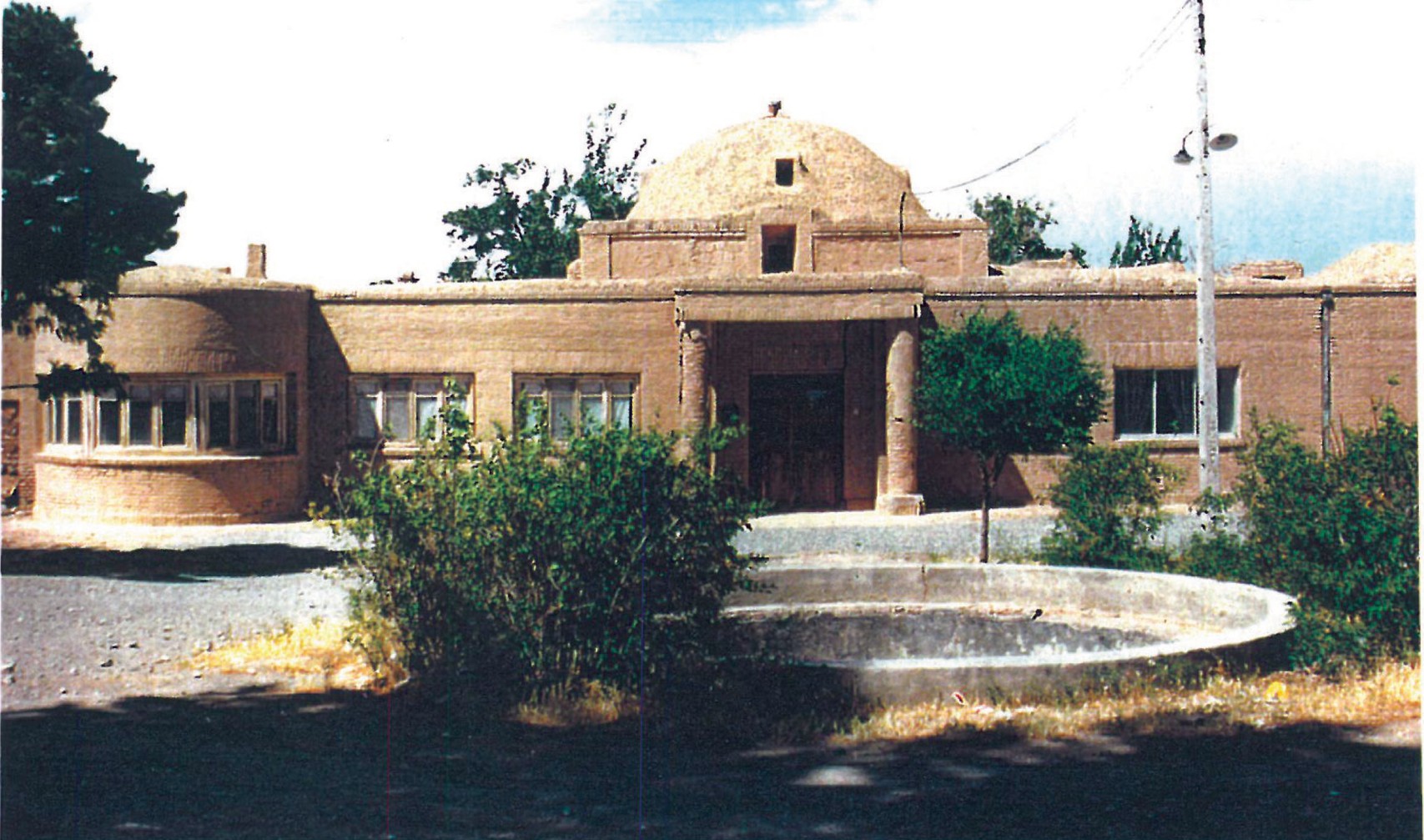 Sheibani castle in Amirabad village near Birjand: a long single-storey adobe complex centred on a domed entrance pavilion, with a circular fountain in the foreground