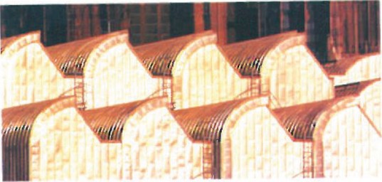 Detail of the titanium-zinc shingle facade on a museum in Cologne by Busmann + Haberer — close-up of the warm-toned overlapping rounded scales catching light
