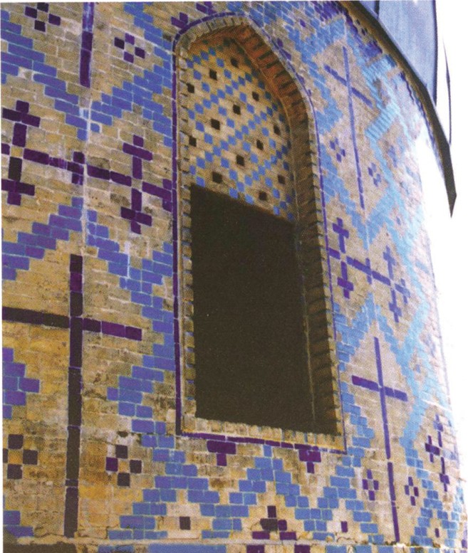 Detail view of the dome drum's entrance opening — pointed-arch aperture in a richly tiled blue-and-white spandrel of geometric Persian tilework