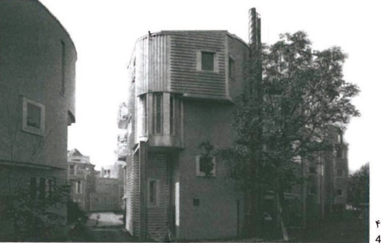 Detail of the Schaudt residential complex in Konstanz — small turreted brick volume rising beside a render-finished party wall, framed by garden trees
