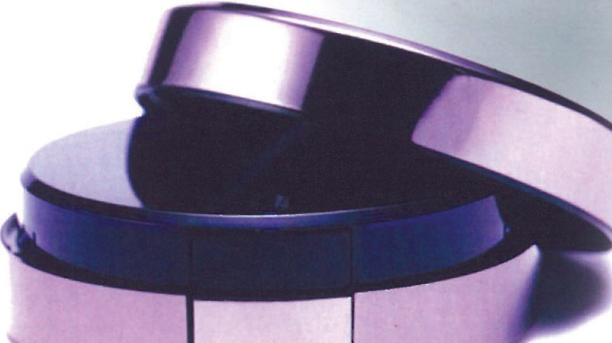 Yves Saint Laurent Nu perfume bottle, a chrome and lavender disc-shaped flacon resting on its side