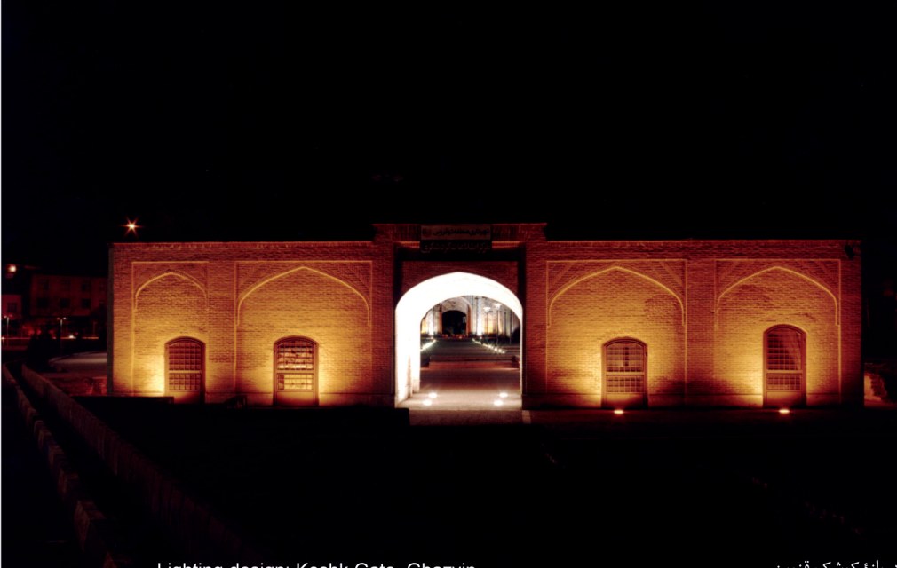 The Koshk Gate of Qazvin illuminated at night, its brick arches and central vaulted passageway lit by ground-level fixtures