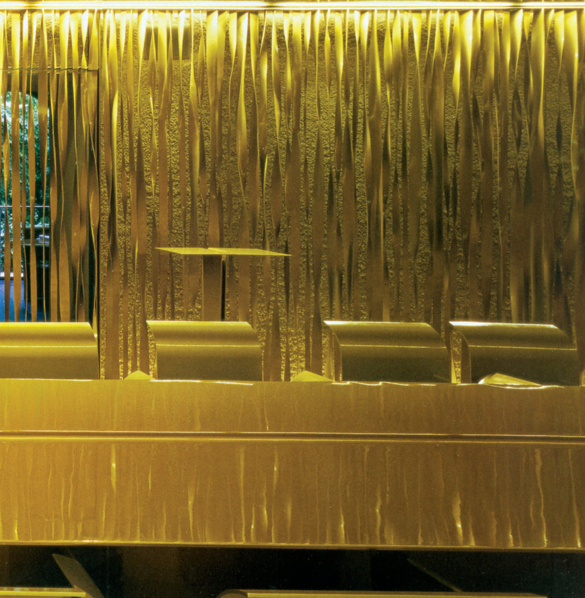 The gold banquet hall with its long 44-seat steel table and walls covered in thousands of suspended gold strips