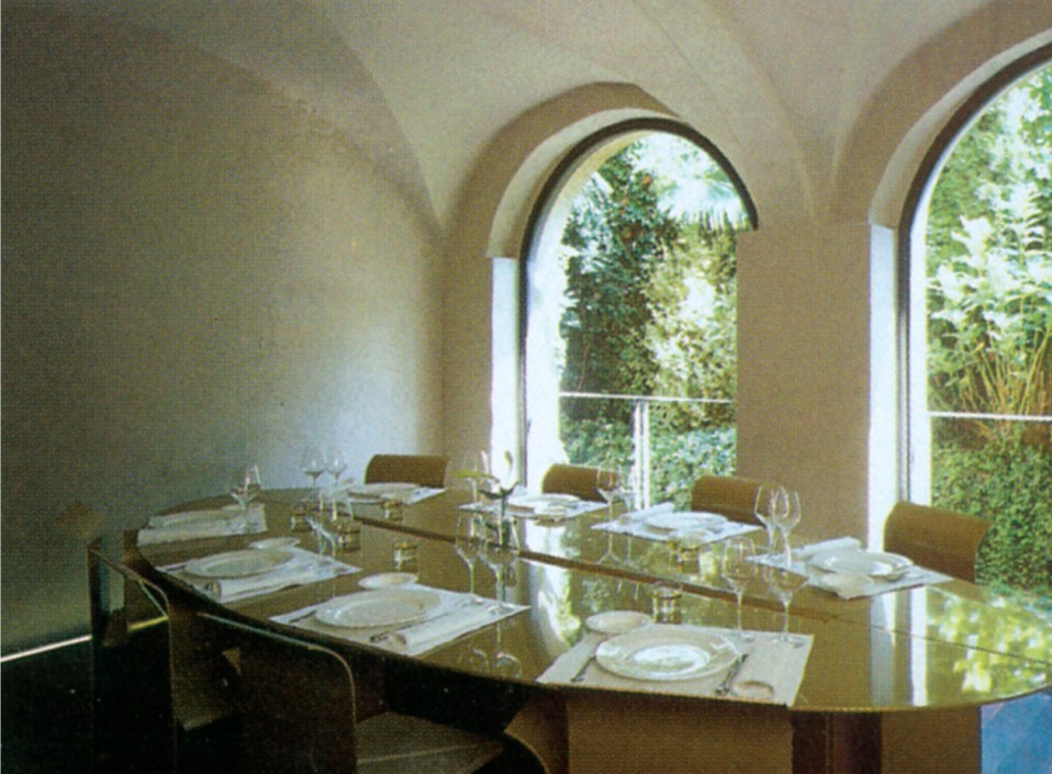 A private dining room set beneath the original house's arched stone vaults, with arched windows opening onto greenery