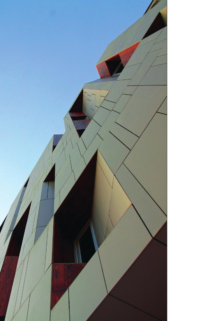 Looking up at the corner of the faceted facade against blue sky