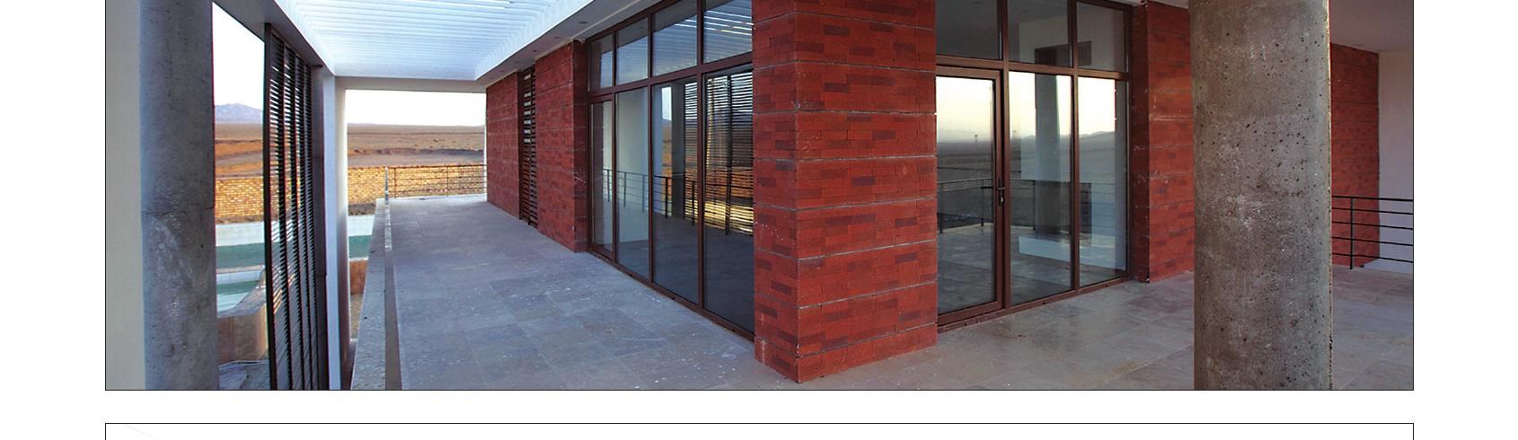 Recessed corridor with red brick wall and full-height glazing