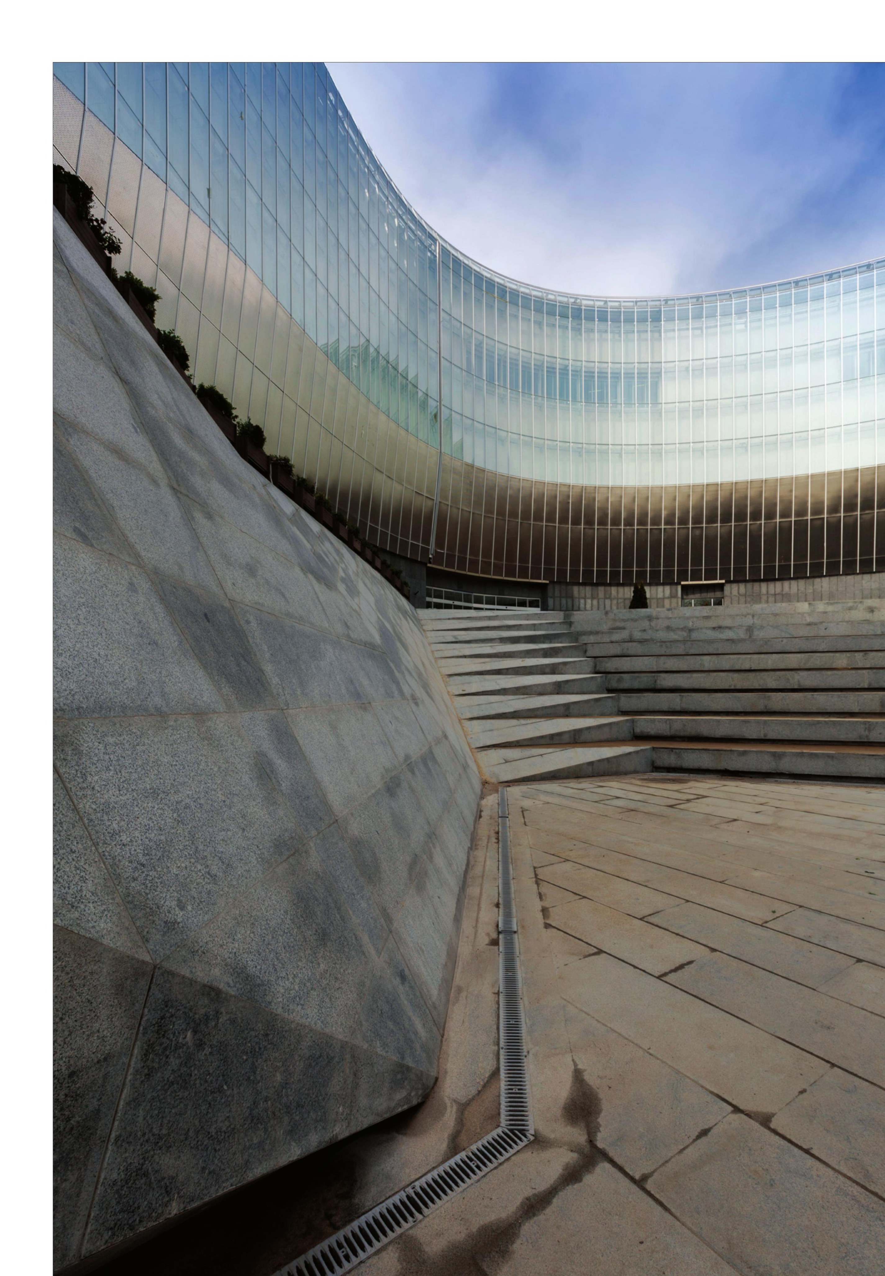 Curving facade above the public stepped plaza — stairs converted to seating terraces.