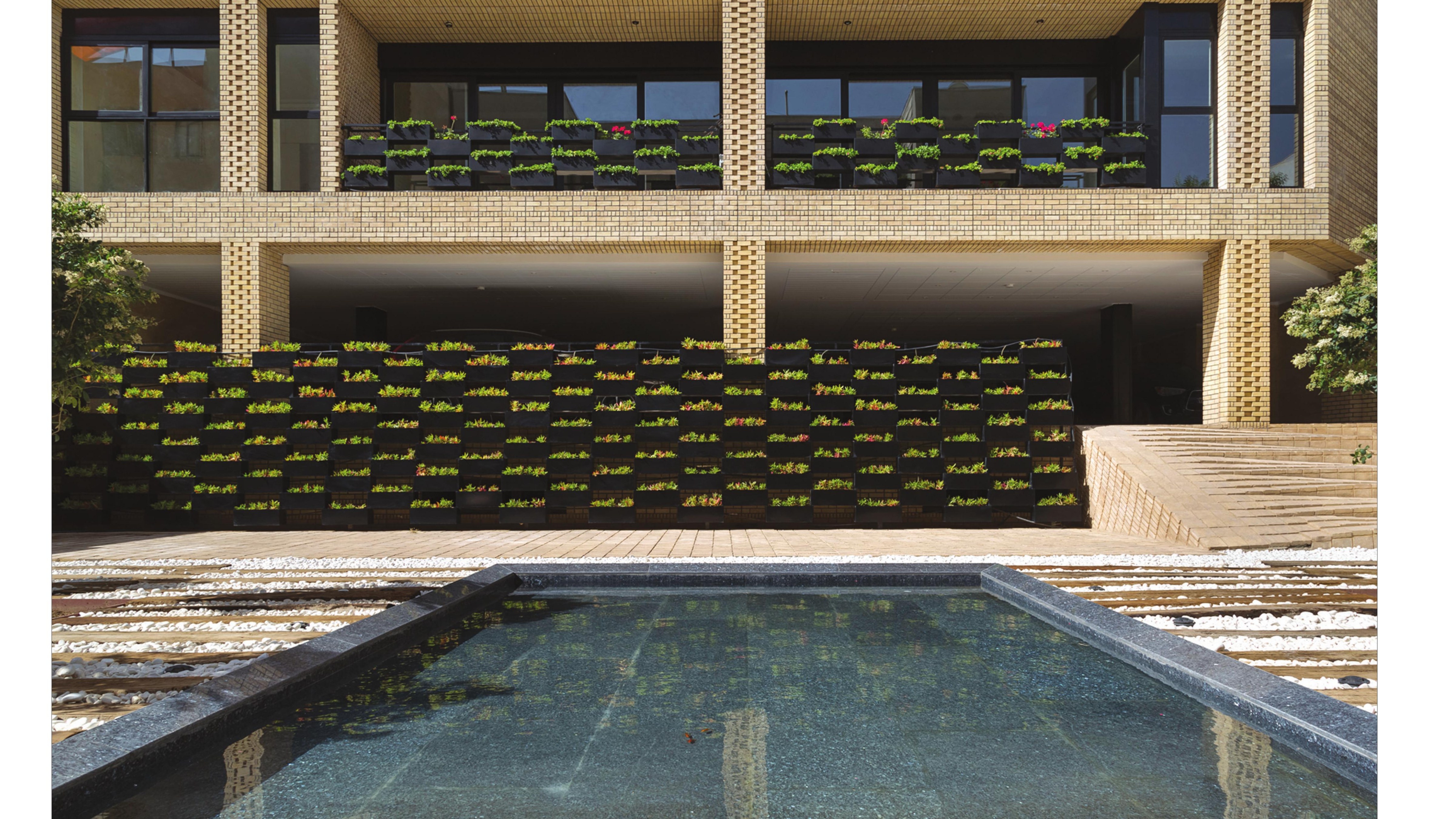 Garden-level: planted wall, pool, and the underside of the residential floors above.