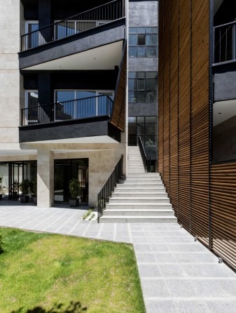 No. 111 Apartment side view at dusk — triangular balconies projecting into the garden, with mature trees in foreground