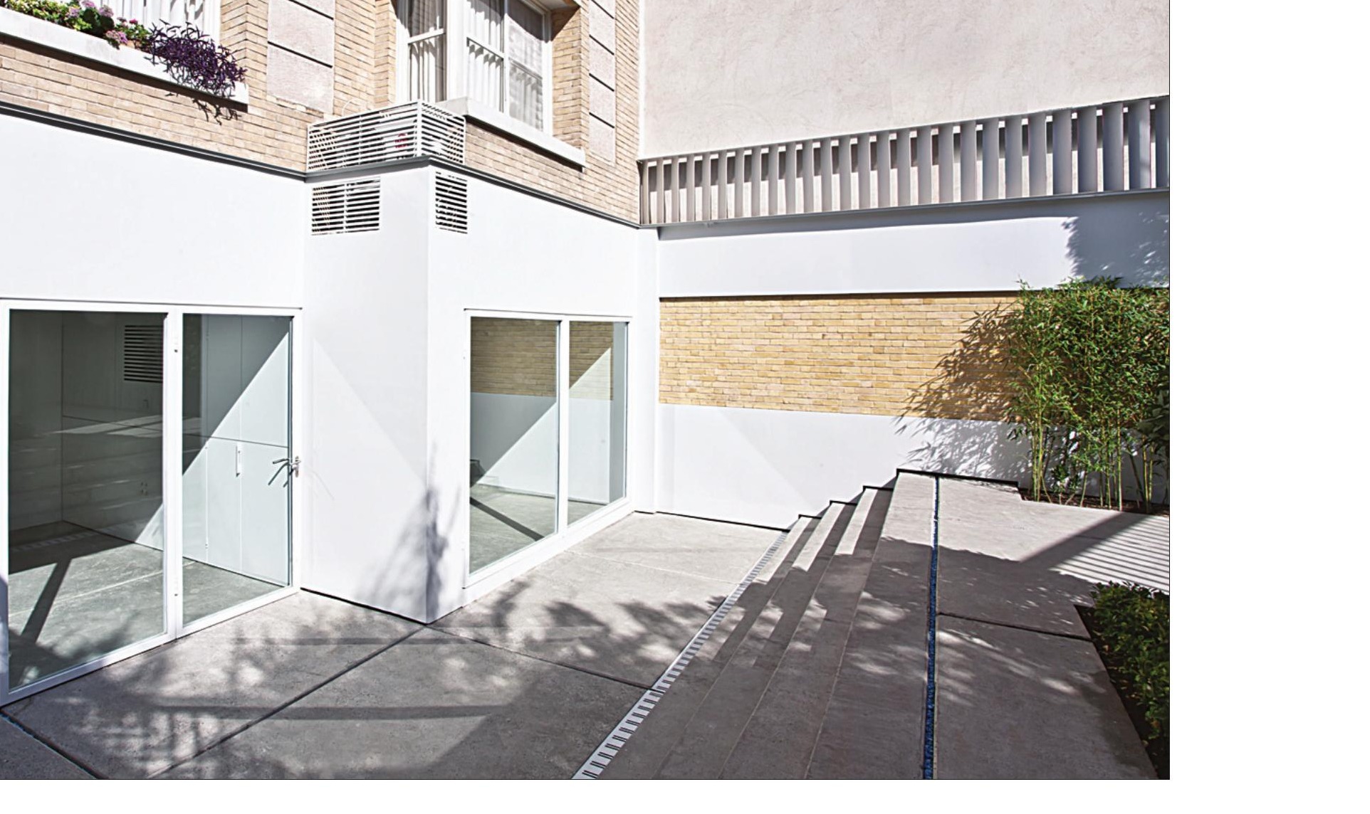 Courtyard facade with white-painted folded metal frame above the brick wall