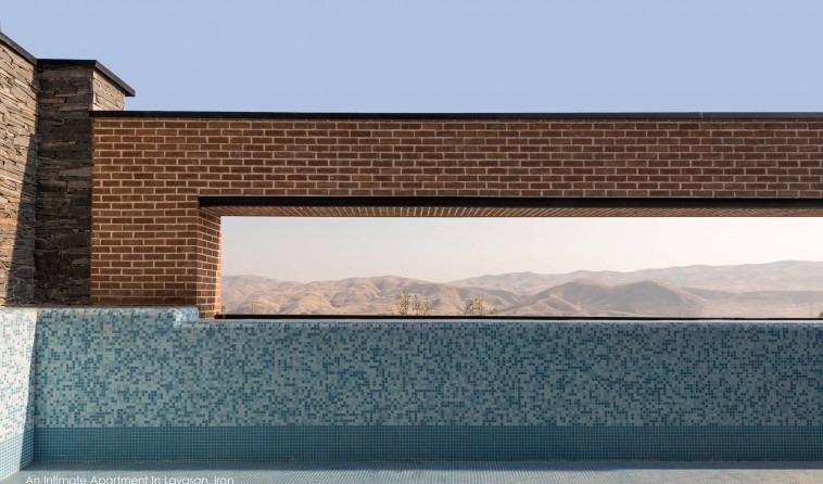 Infinity pool edge with a horizontal slot view through the brick wall toward the mountains of Lavasan